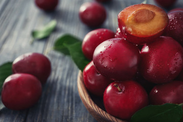 Bowl with ripe fresh plums on table, closeup
