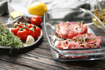 Baking dish with fresh raw steaks and vegetables on table