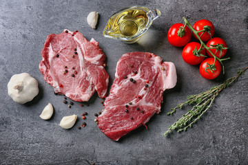 Composition with fresh raw steaks, vegetables and spice on table