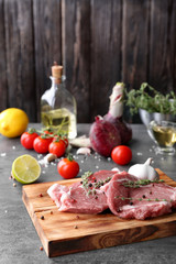 Board with fresh raw steaks and thyme on table