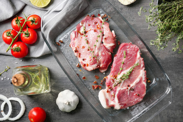 Baking dish with fresh raw steaks on table