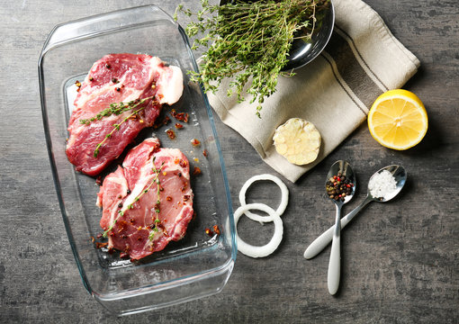 Baking dish with fresh raw steaks on table