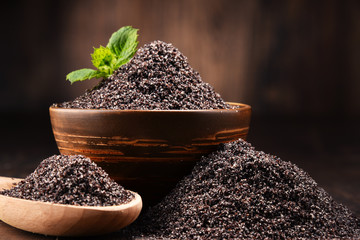 Composition with bowl of poppy seeds on wooden table