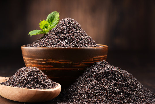Composition with bowl of poppy seeds on wooden table