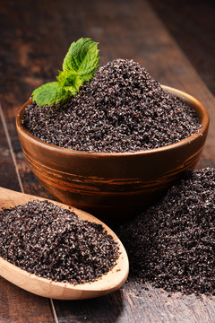 Composition with bowl of poppy seeds on wooden table