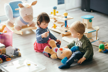little girl and boy playing with toys by the home - obrazy, fototapety, plakaty