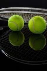 Close up of fluorescent yellow tennis balls with racket with