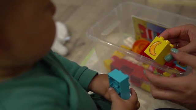 Close up of hands playing with colorful interlocking plastic bricks of meccano