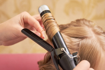 Blonde hair and curling iron. Hair styling tool, close up. Buy curling iron online.