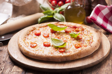 Italian pizza with tomato topped with melted golden cheese, herbs and basil