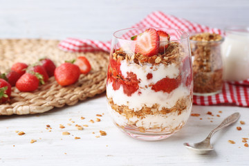 Tasty dessert with strawberry in glass on wooden table
