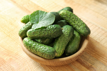 Green fresh cucumbers in bowl on wooden table