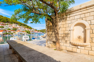 Narrow street with water tap in  Pucisca port with fishing boats, Brac island, Croatia