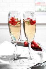 Glasses of delicious wine with strawberry on table
