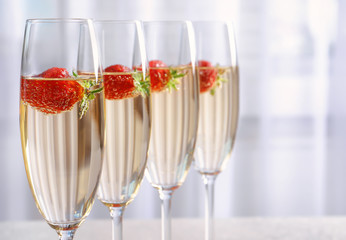 Glasses of delicious wine with strawberry on light background