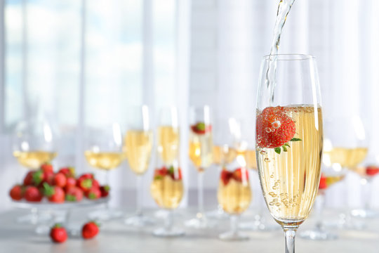 Pouring delicious strawberry wine into glass on blurred background