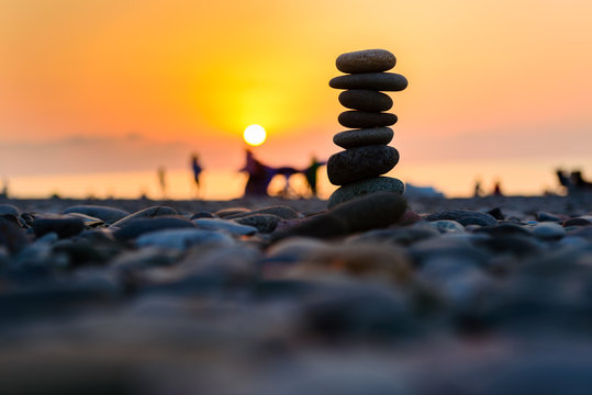 Stones pyramid on sand symbolizing zen, harmony, balance. Black sea at sunset in the background.