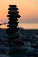 Stones pyramid on sand symbolizing zen, harmony, balance. Black sea at sunset in the background.