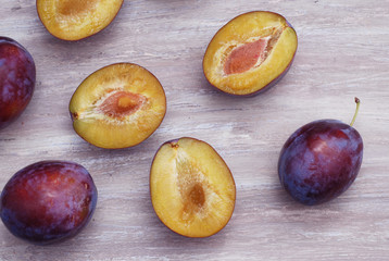 Fresh ripe plums on a white wood background, rustic style, selective focus