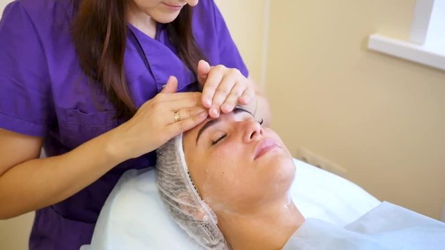 Cosmetologist Applying cream to the face and massages woman. Cosmetic procedures Mechanical cleaning of the face. Cosmetology.