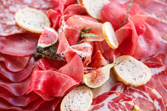 Italian antipasti and appetizers. board with slices prosciutto, salami, dried pork, salami ham with herbs.