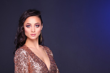 Beautiful young woman in evening dress on black background.