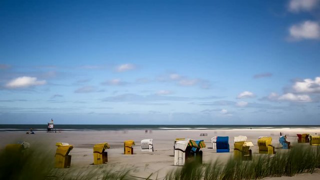 Zeitraffer, Wolken ziehen &uuml;ber den Strand mit Strandk&ouml;rben auf der Nordseeinsel Juist in Ostfriesland, Deutschland, Europa.