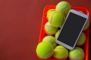 High angle view of mobile phone and tennis balls in basket