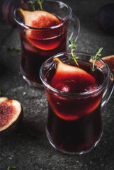Fall and winter red sangria cocktail with thyme and figs, on black stone table, copy space