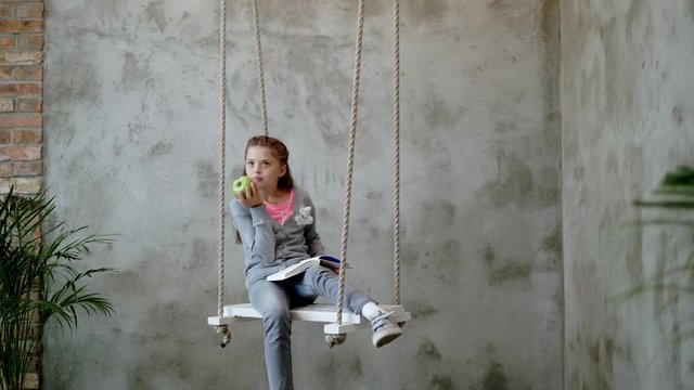 Little girl with a book on a swings
