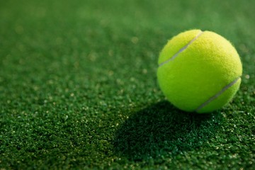 Close up of fluorescent yellow tennis ball on grass