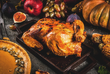 Thanksgiving Day food. Roasted whole chicken or turkey with autumn vegetables and fruits: corn,...