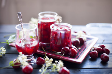 jam from cherry, in cans. winter desserts. dark photo. spring white flowers