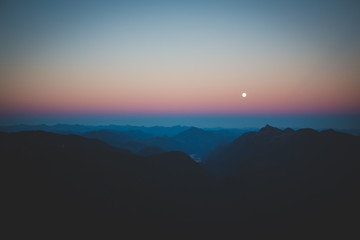 View of the moon from a mountain peak at sunset