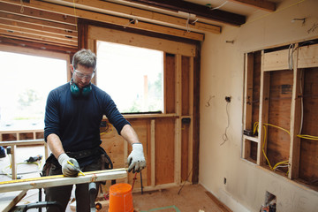 Carpenter measuring two by four - 2X4- wood inside
