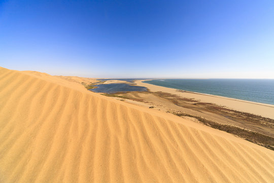 Sand dunes modeled by wind meet the Atlantic Ocean and lagoons in Walvis Bay Namib Desert Erongo Region Namibia Southern Africa