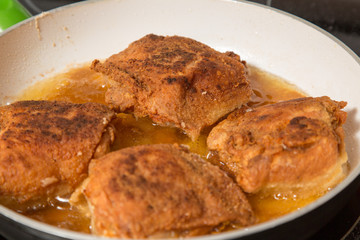 golden brown chicken thighs frying in skillet on stove
