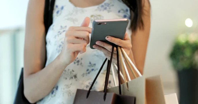 Close up of woman using cellphone and holding shopping bags