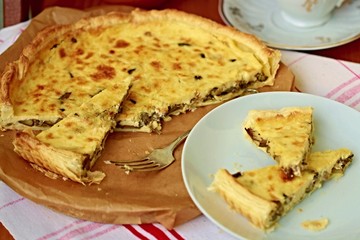 Mushroom quiche in triangle slices on white plate with silver fork next to it and big piece not sliced