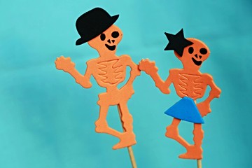 Two funny orange Halloween skeletons - man and woman in love with dark violet background