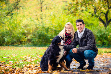 Couple with dog enjoying autumn in nature playing with the pet