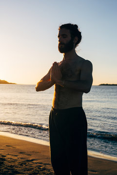 Bearded man meditating on beach