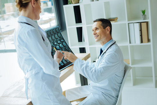 Joyful professional neurologists discussing an electroencephalogram