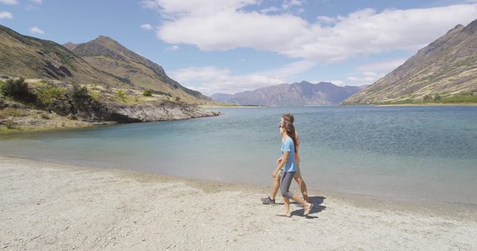New Zealand travel happy tourist couple walking at beach shore of lake Hawea nature landscape. Near Wanaka, Otago Region.