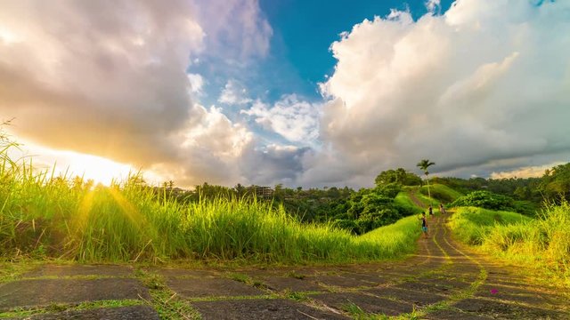 Sunset timelapse and People walk on Campuhan Ridge Walk, path on top of grassy hill. Popular trekking place in Ubud, Gianyar Regency of Bali. UBUD, INDONESIA - Jule, 2017
