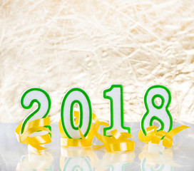 Happy 2018 New Year numbers plus party ribbons on glass table with golden background