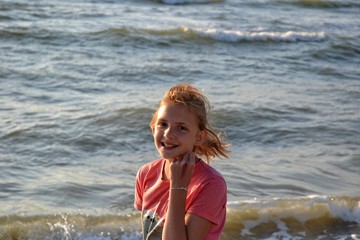 Mädchen steht am Meer und lächelt nach vorne