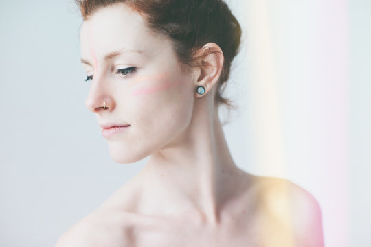 Stylized studio beauty shot of topless woman wearing facepaint