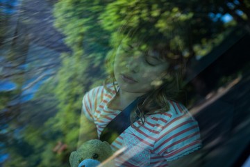 Teenage girl with teddy bear sleeping in the back seat of car