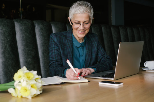Smiling Senior Businesswoman Writing Notes while Working